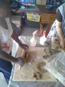 Adults rolling out the clay to make moulds